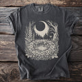 Dark t-shirt with a whimsical forest, moon, and mushroom design.