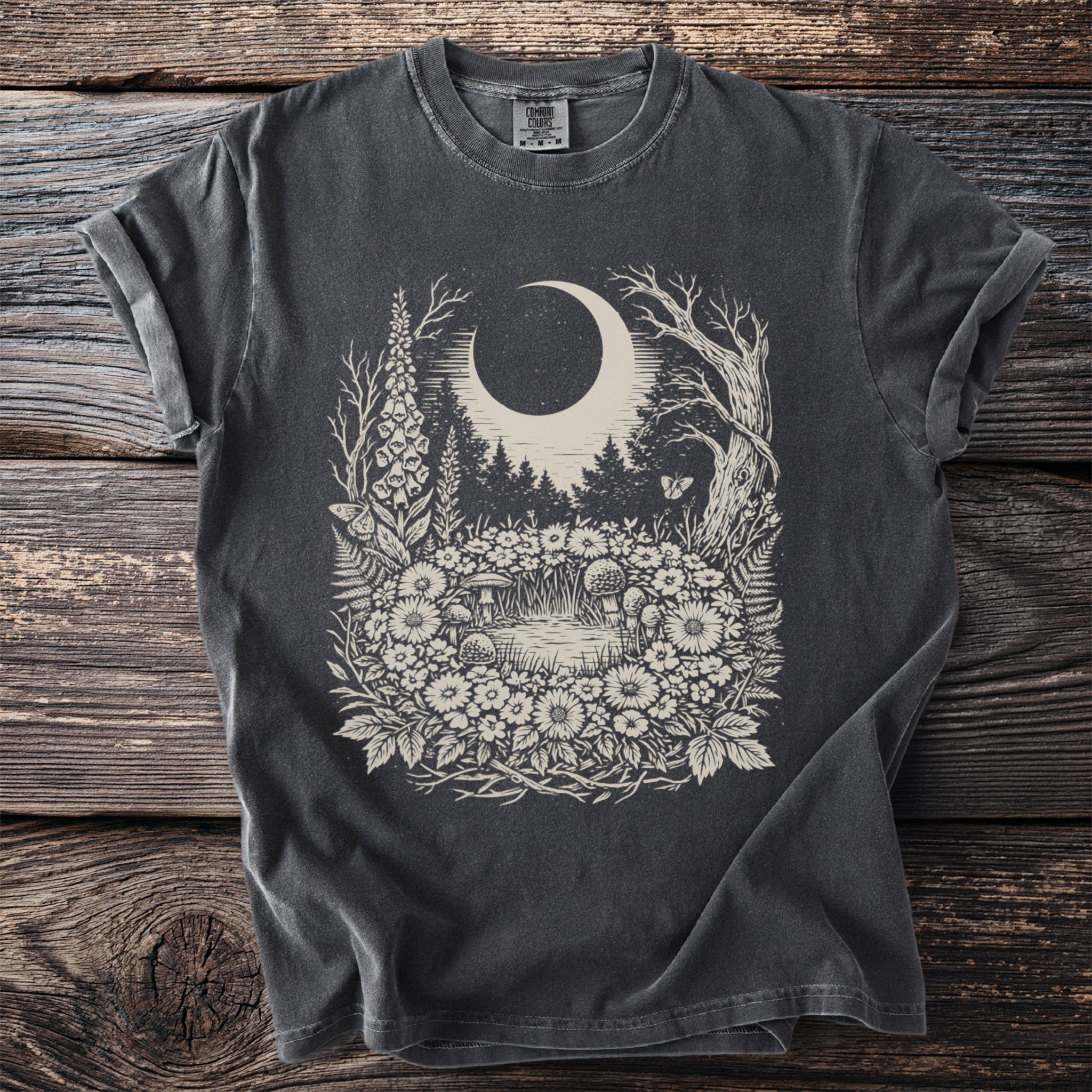 Dark t-shirt with a whimsical forest, moon, and mushroom design.