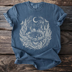 Blue t-shirt with a circular forest design featuring a crescent moon, mushrooms, fairies, and butterflies.