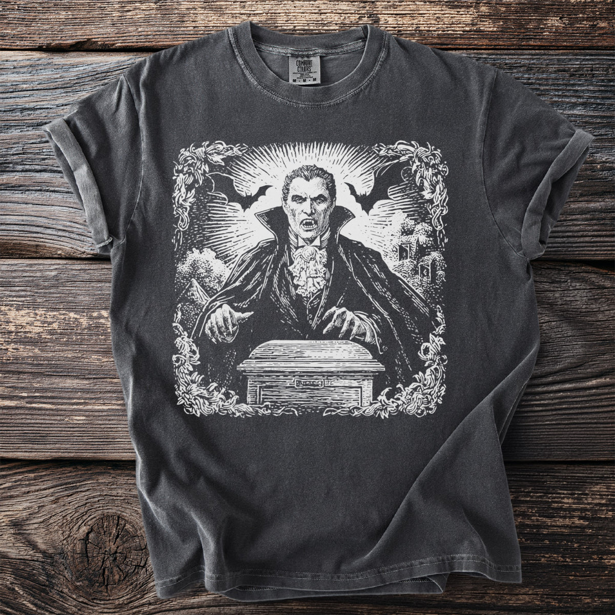 Dark t-shirt with a white graphic of a vampire over a coffin.