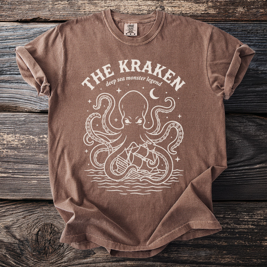 Brown t-shirt with a white graphic of a kraken, ship, and moon, reading "The Kraken".
