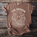 Brown t-shirt with a white graphic of a kraken, ship, and moon, reading "The Kraken".