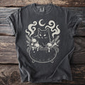 Black cat in a cauldron with ornaments, celestial elements, and sprigs.