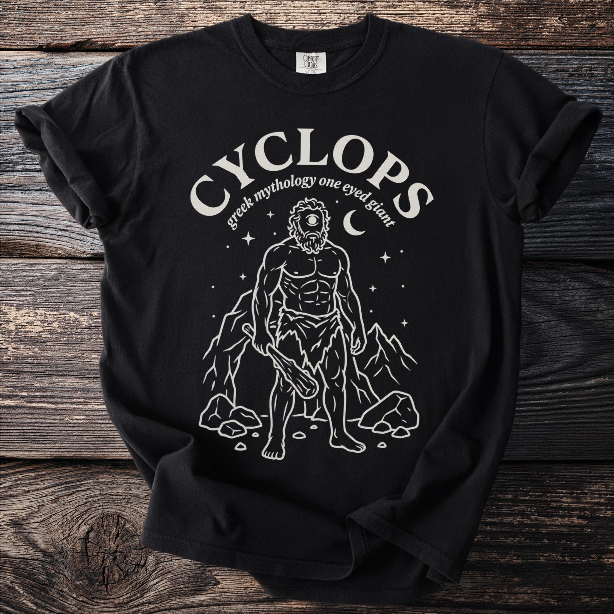 Black t-shirt with white illustration of a Cyclops, mountains, and stars.