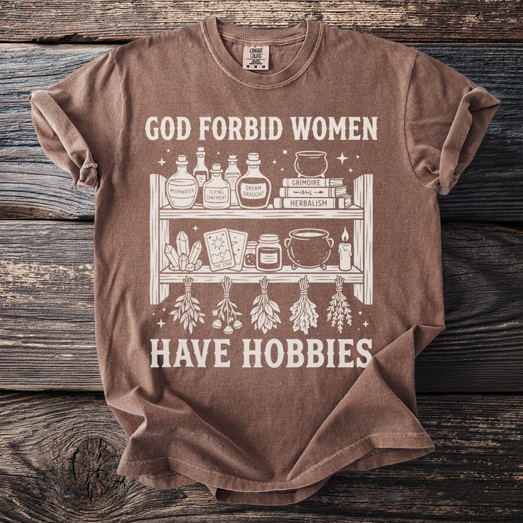 T-shirt with graphic reading "God forbid women have hobbies" and mystical illustrations.