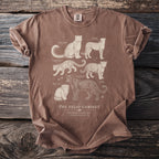 Brown t-shirt featuring illustrations of snow leopard, cheetah, clouded leopard, black leopard, jaguar, and Pallas's cat.