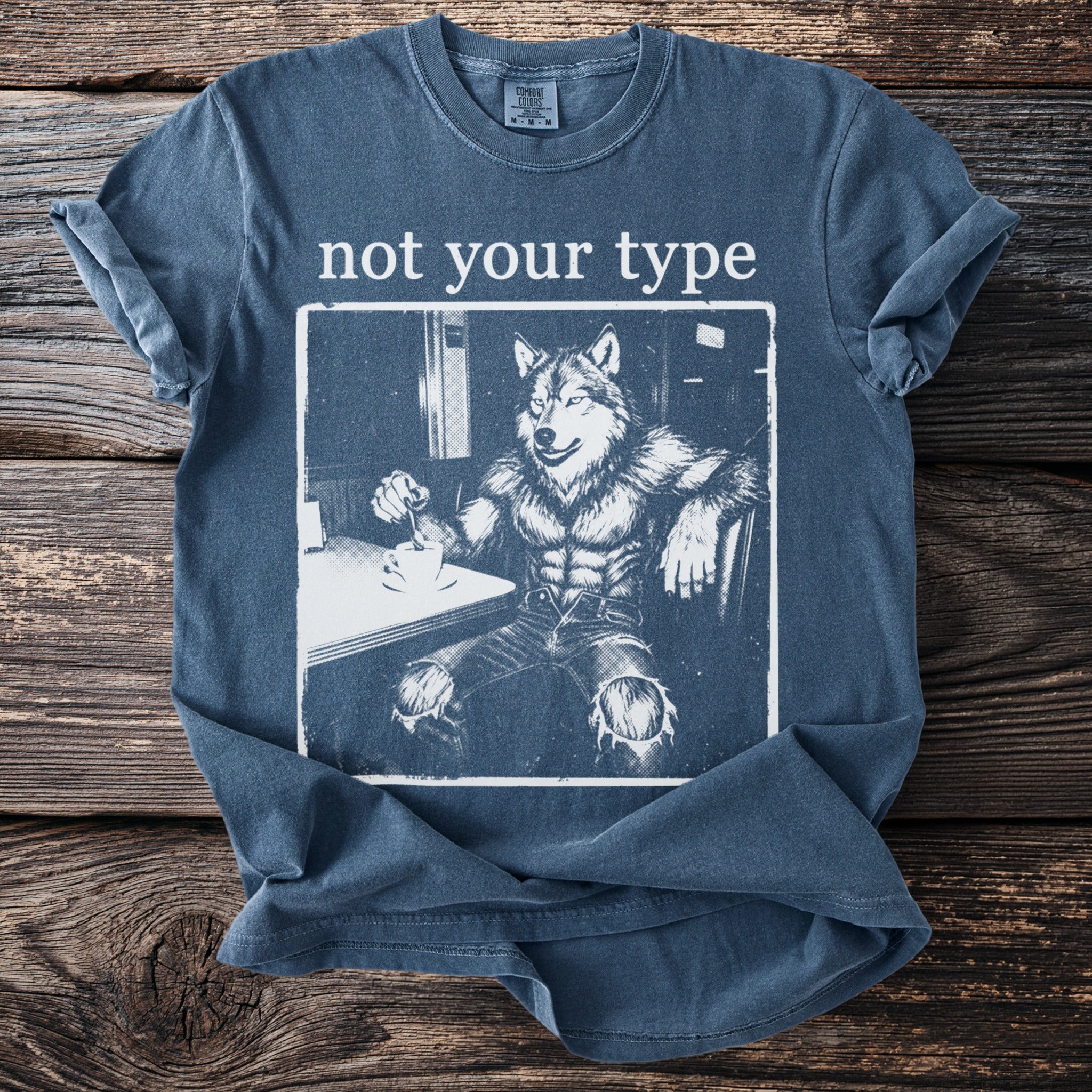 Blue t-shirt with white text "not your type" and a drawing of a muscular werewolf by a coffee cup.