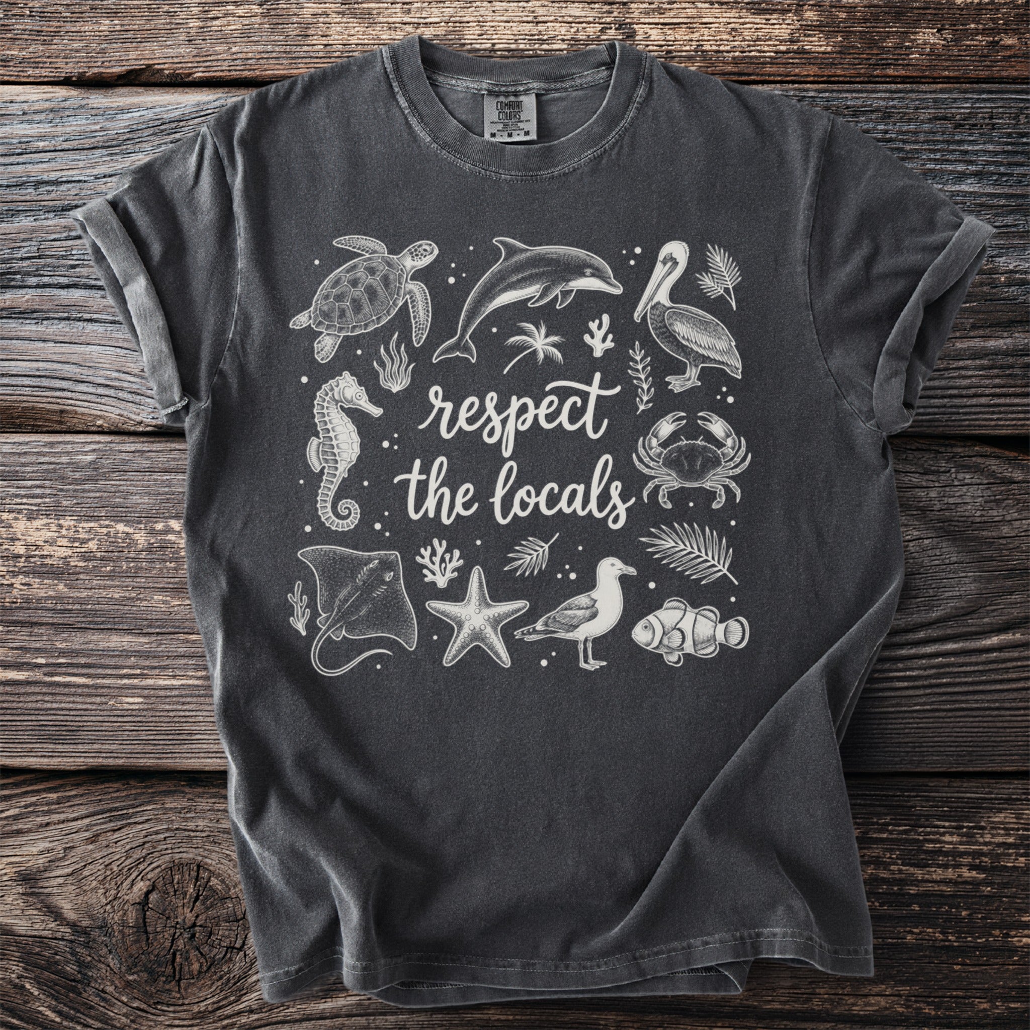 Dark grey t-shirt with white line-art of sea creatures and text "respect the locals."