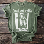 Green t-shirt with "feral but polite" text and werewolf graphic.