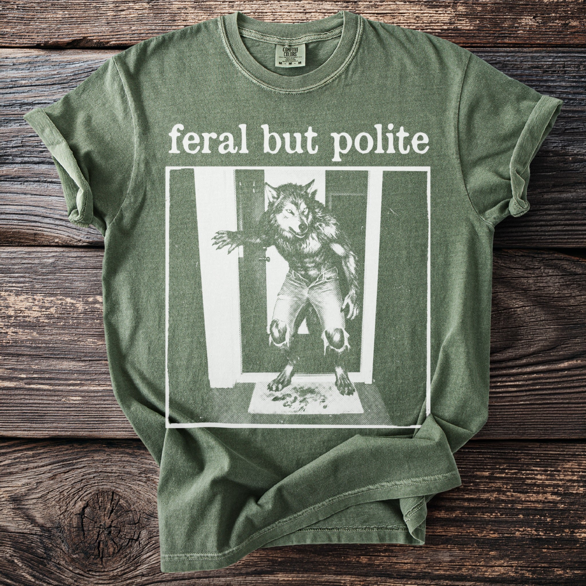 Green t-shirt with "feral but polite" text and werewolf graphic.