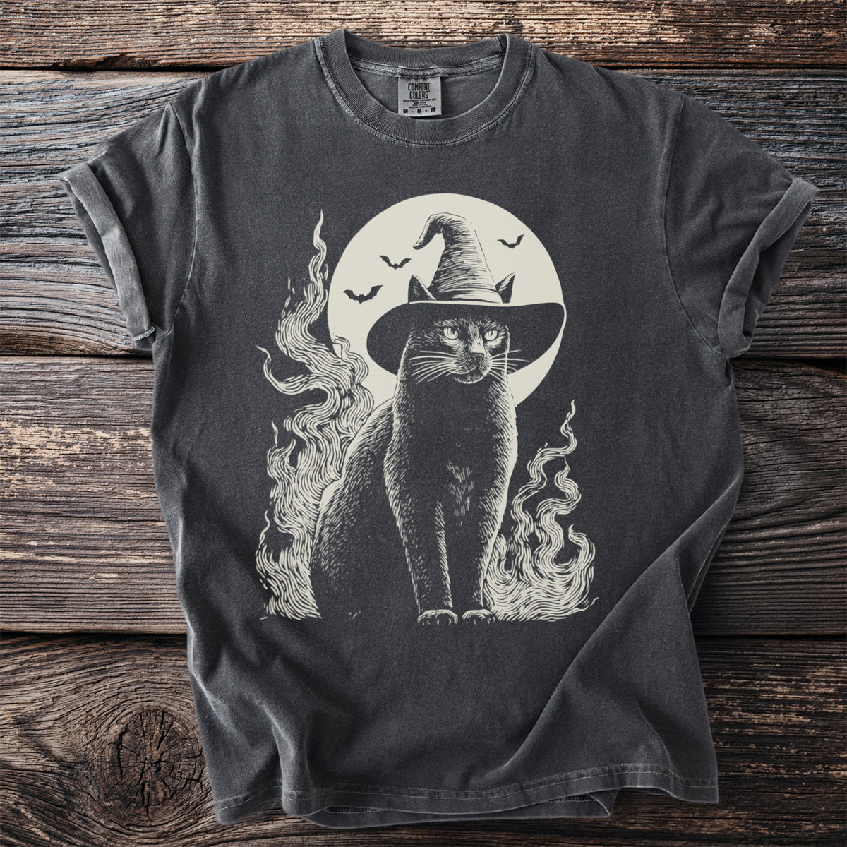 Black cat wearing a witch hat with bats and moon, on a charcoal t-shirt.