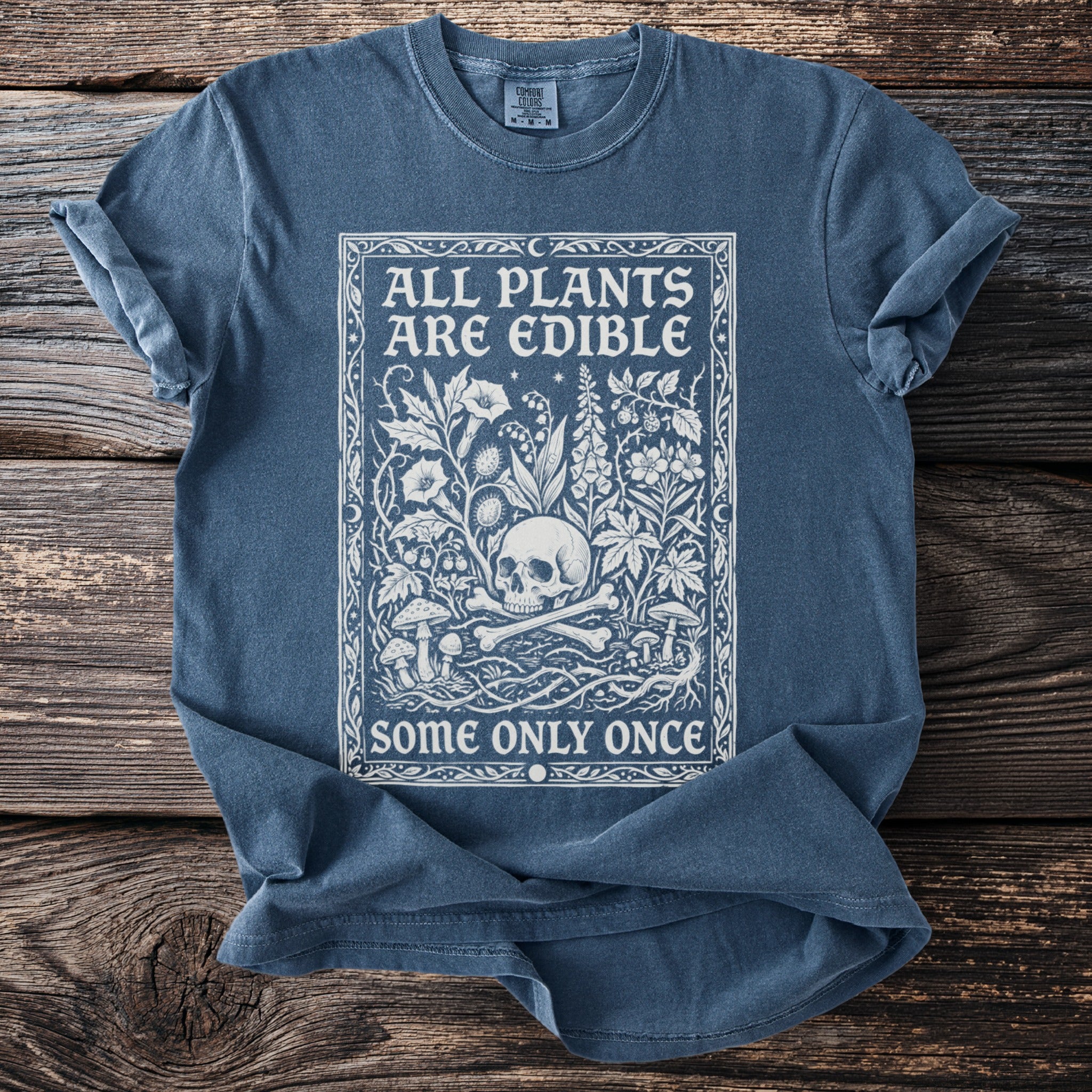 Blue t-shirt with white text and illustration of skull, bones, and plants.