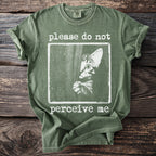 Green t-shirt with a distressed graphic of a cat peering out with text "please do not perceive me".