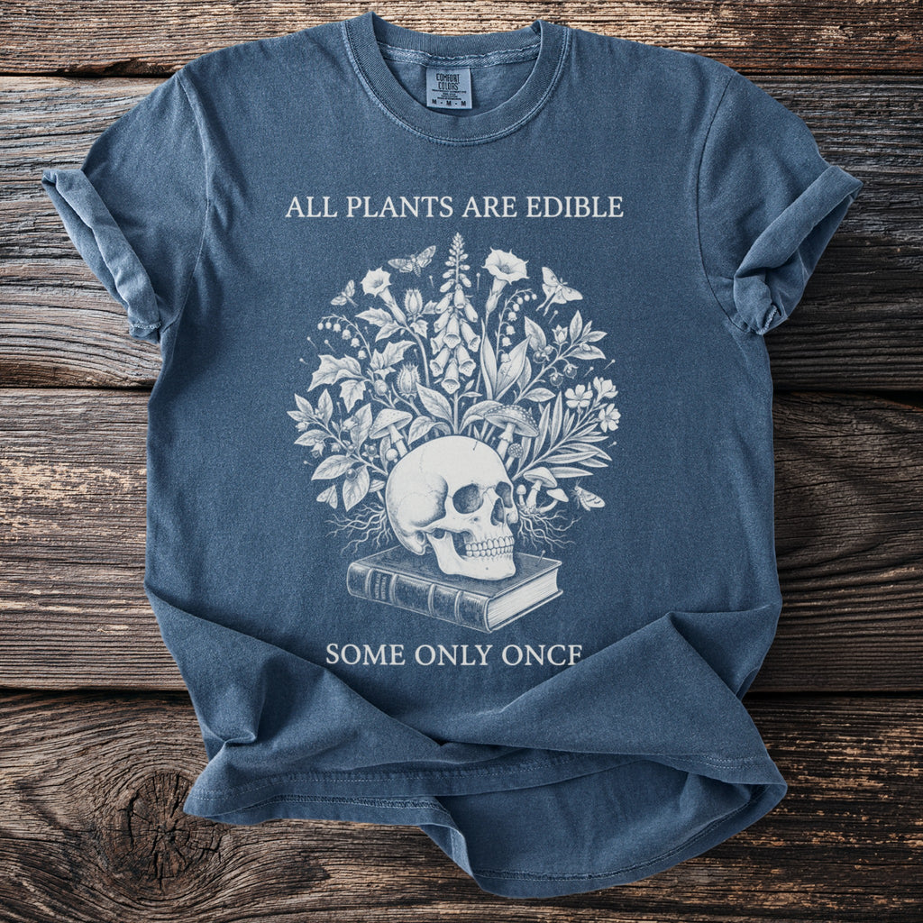 T-shirt with skull, book, plants, and text "ALL PLANTS ARE EDIBLE SOME ONLY ONCF".