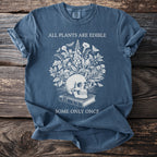 T-shirt with skull, book, plants, and text "ALL PLANTS ARE EDIBLE SOME ONLY ONCF".