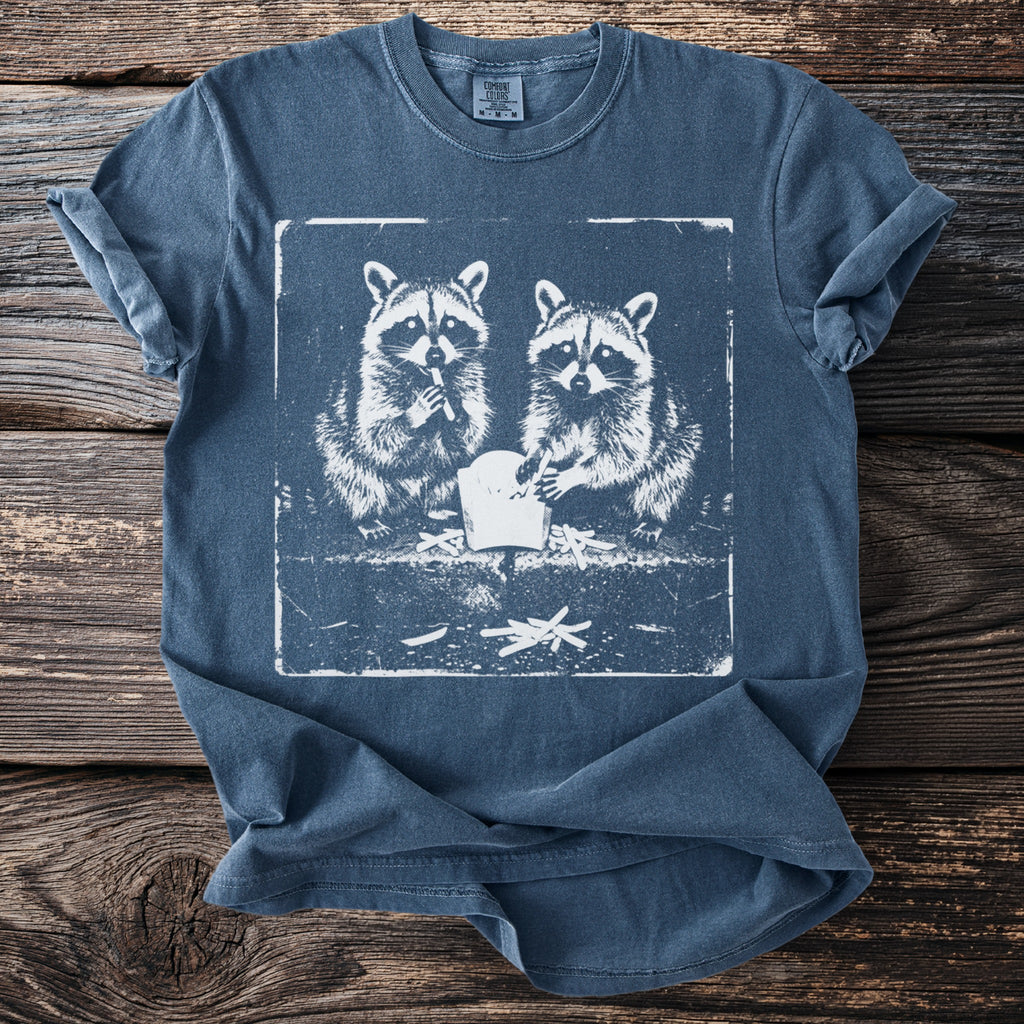 T-shirt with a graphic of two raccoons eating french fries inside a distressed square.