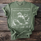 Green t-shirt with ravens graphic and text "support your local unkindness".