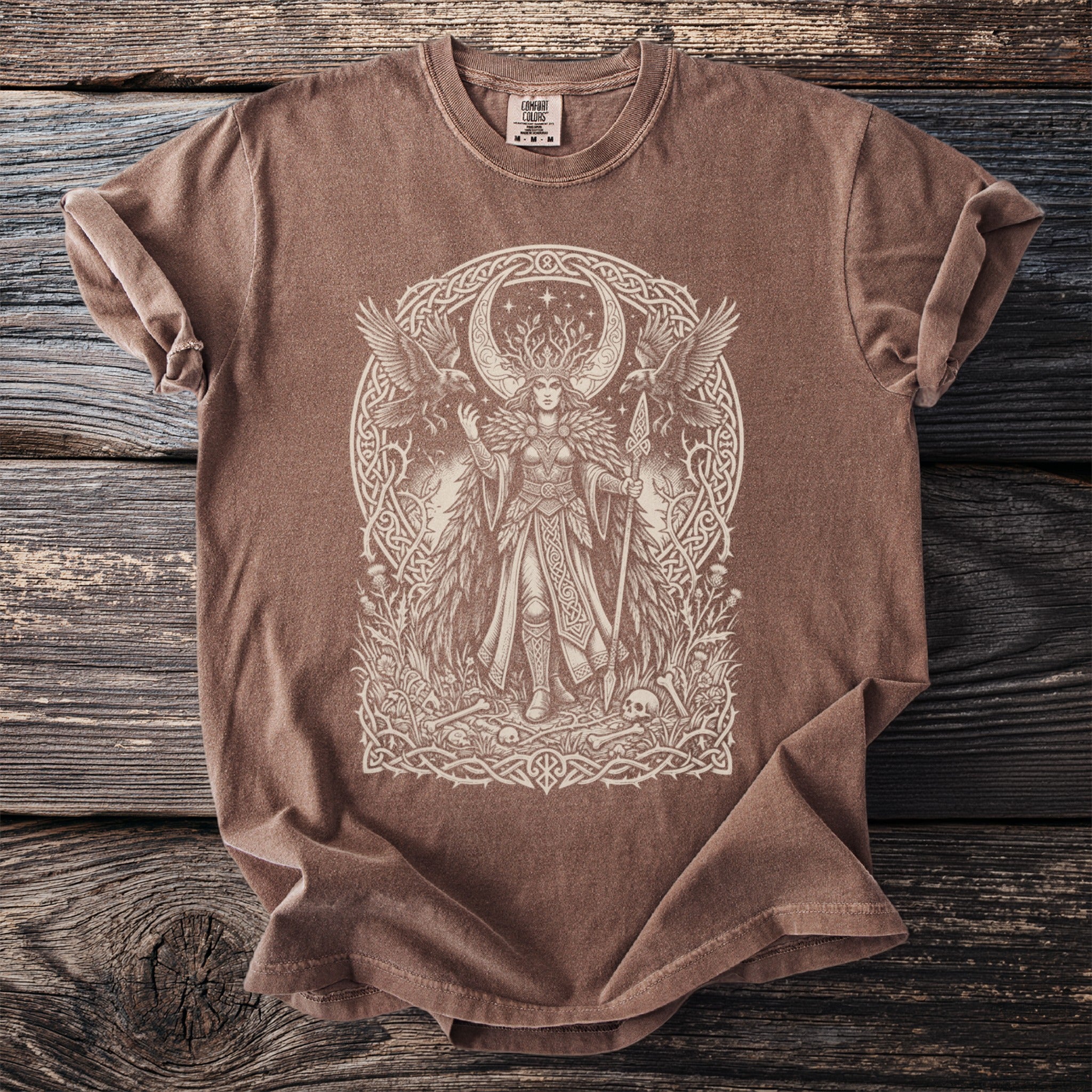 Brown t-shirt with a detailed cream line drawing of a mythical goddess surrounded by ravens and Celtic knotwork.