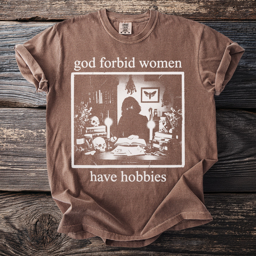 Brown t-shirt with "god forbid women have hobbies" and skull graphic.