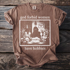 Brown t-shirt with "god forbid women have hobbies" and skull graphic.