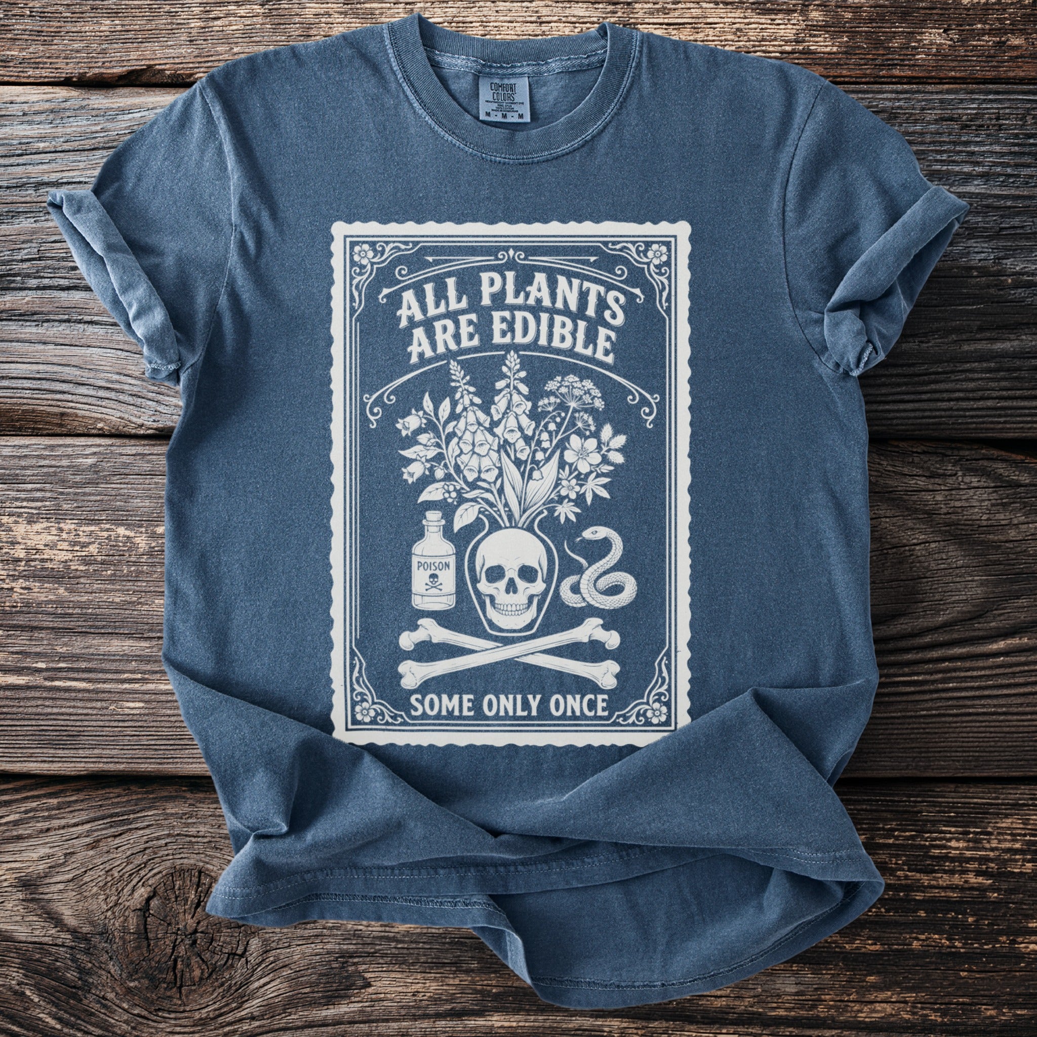 Blue t-shirt with "ALL PLANTS ARE EDIBLE SOME ONLY ONCE" text and botanical skull graphic.