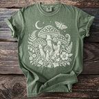 Olive green t-shirt with white mushroom, moon, moth, and floral design.