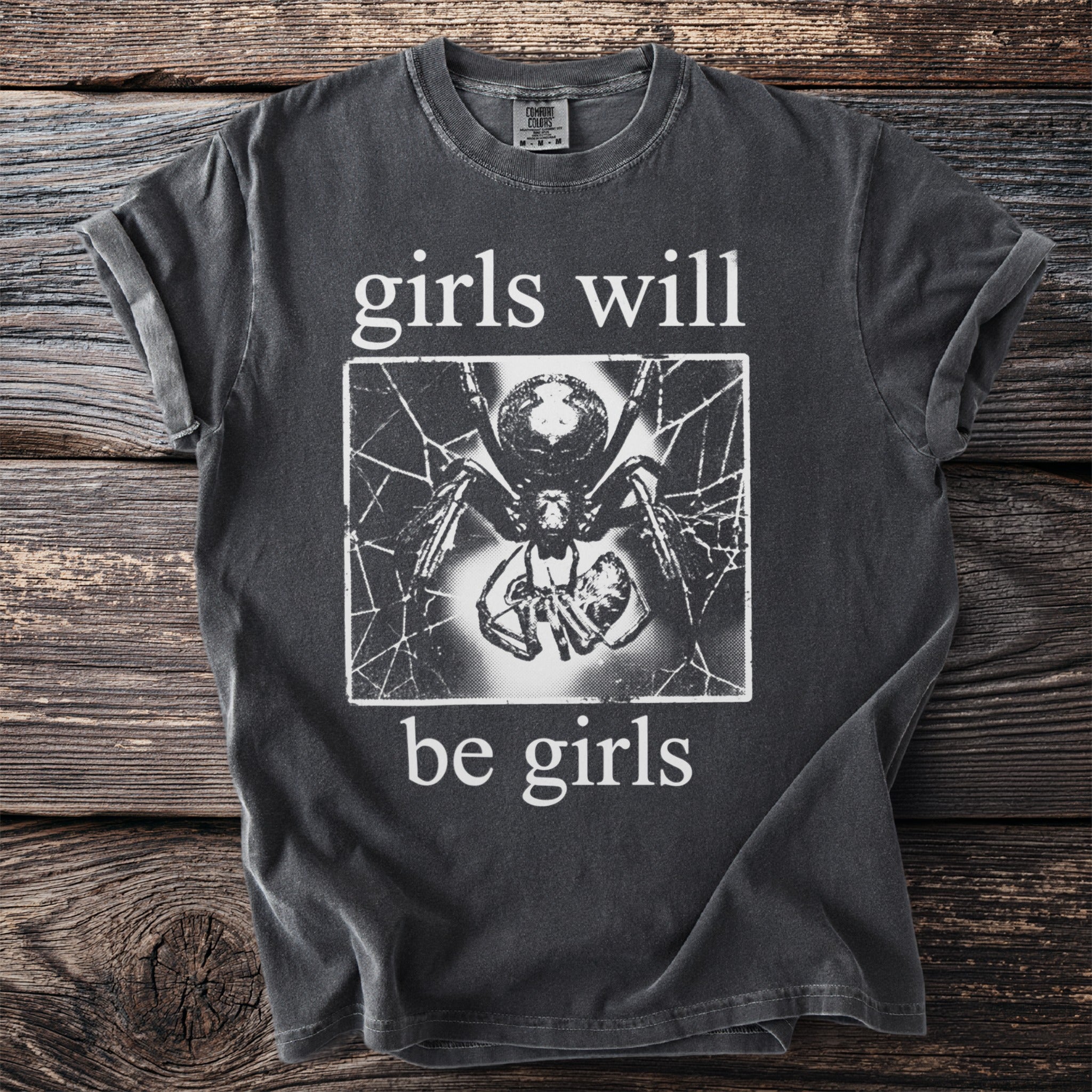 Gray t-shirt with white text "girls will be girls" and a spider graphic.