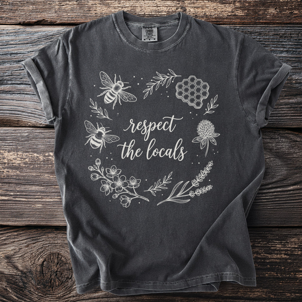 Dark gray t-shirt with white floral design, two bees, and text "respect the locals".
