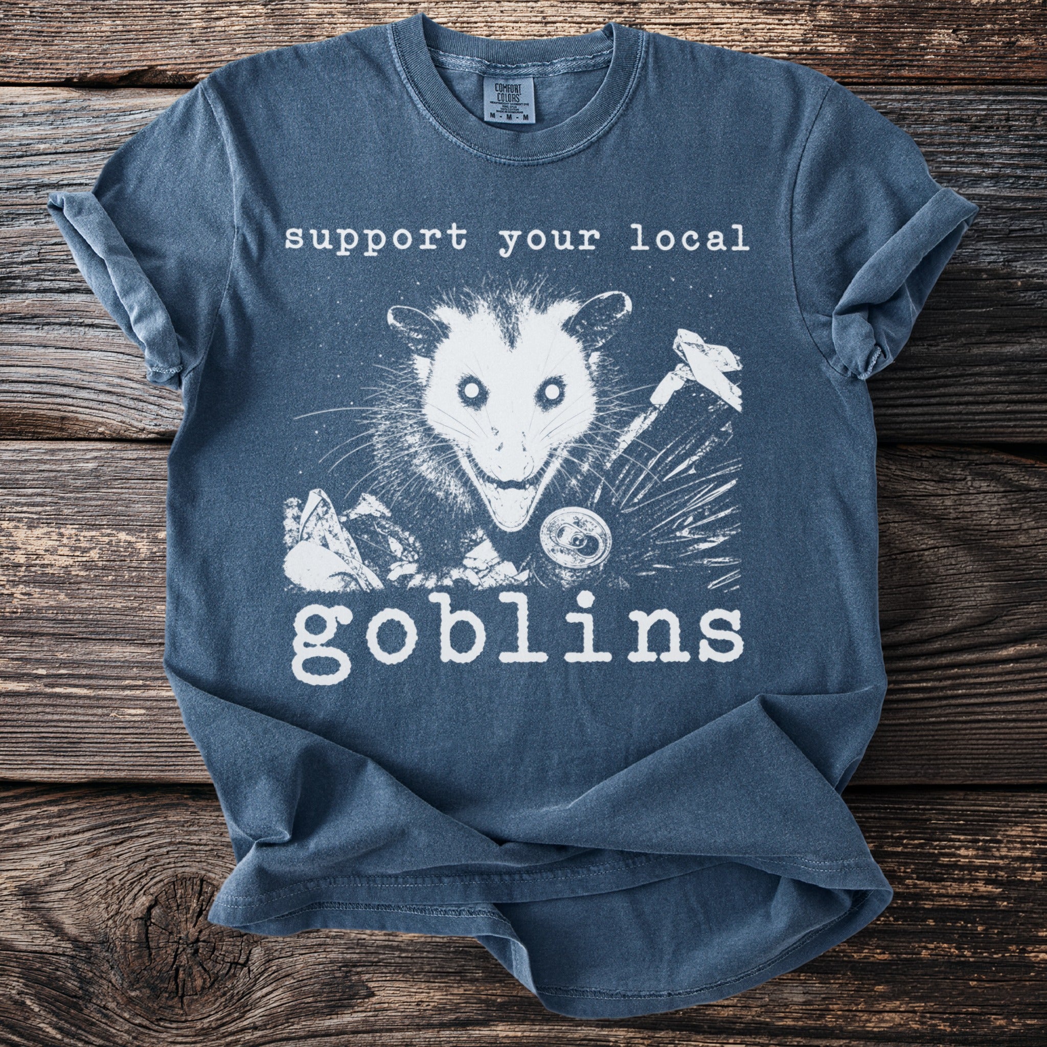 T-shirt with "Support Your Local Goblins" and an opossum graphic.