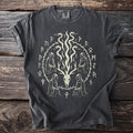 Dark gray t-shirt with a goat skull and two serpents in a ring of runes, with four hooded figures at the corners.