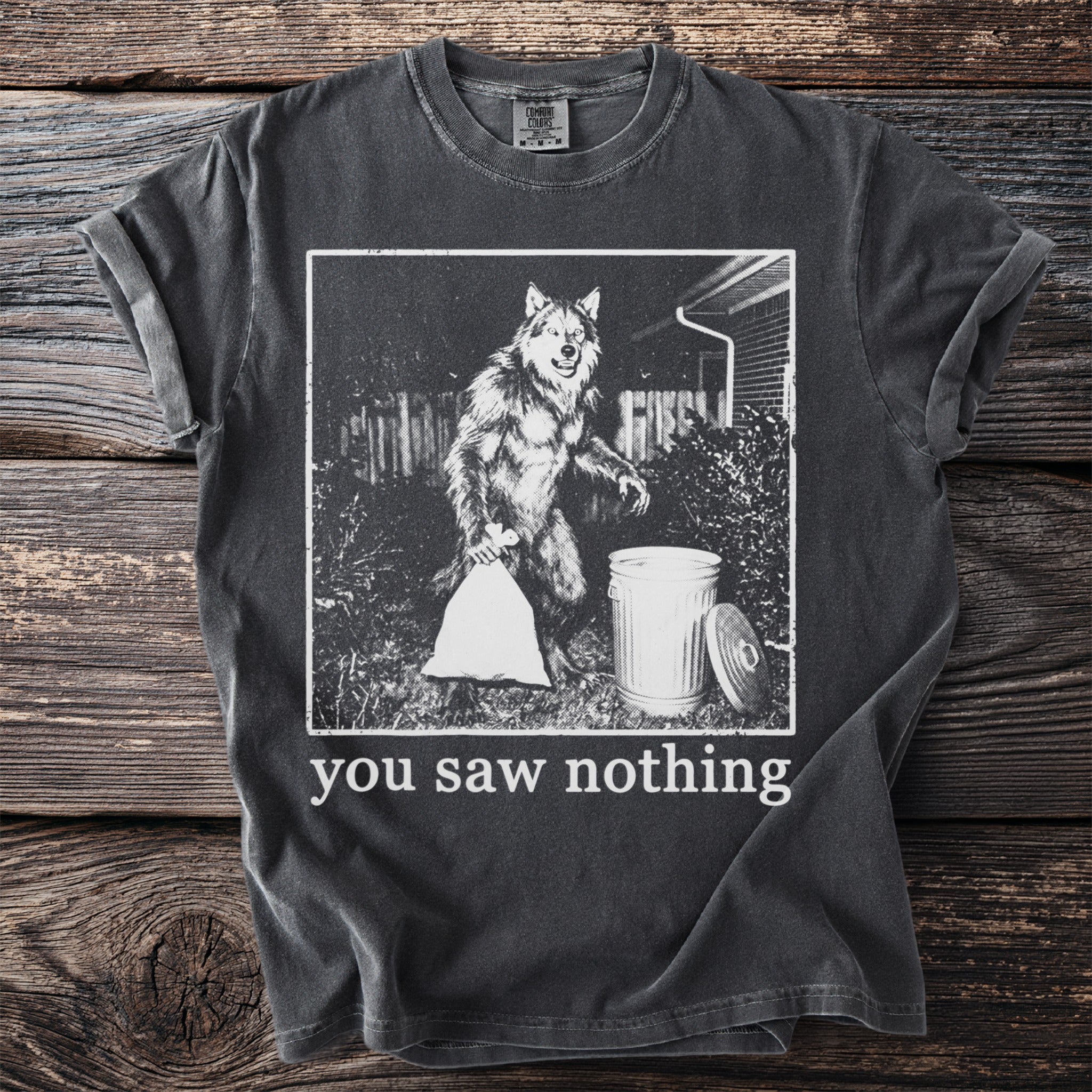 Dark grey t-shirt with graphic of werewolf taking out trash, reads "you saw nothing".