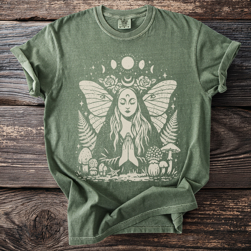 Olive green t-shirt with a light graphic of a praying woman with butterfly wings, moon phases, and mushrooms.