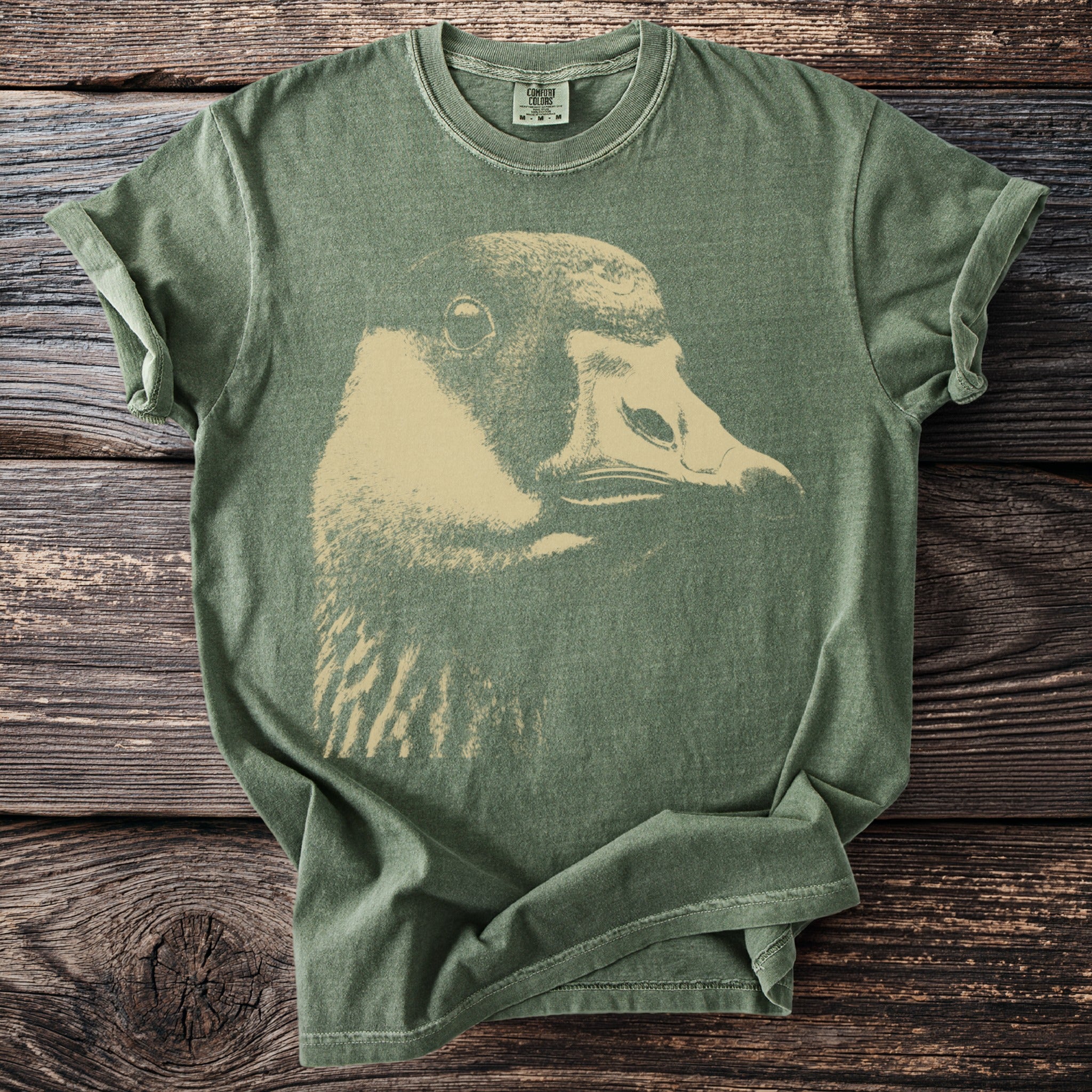 Green t-shirt with a faded beige duck graphic, size M tag displayed.