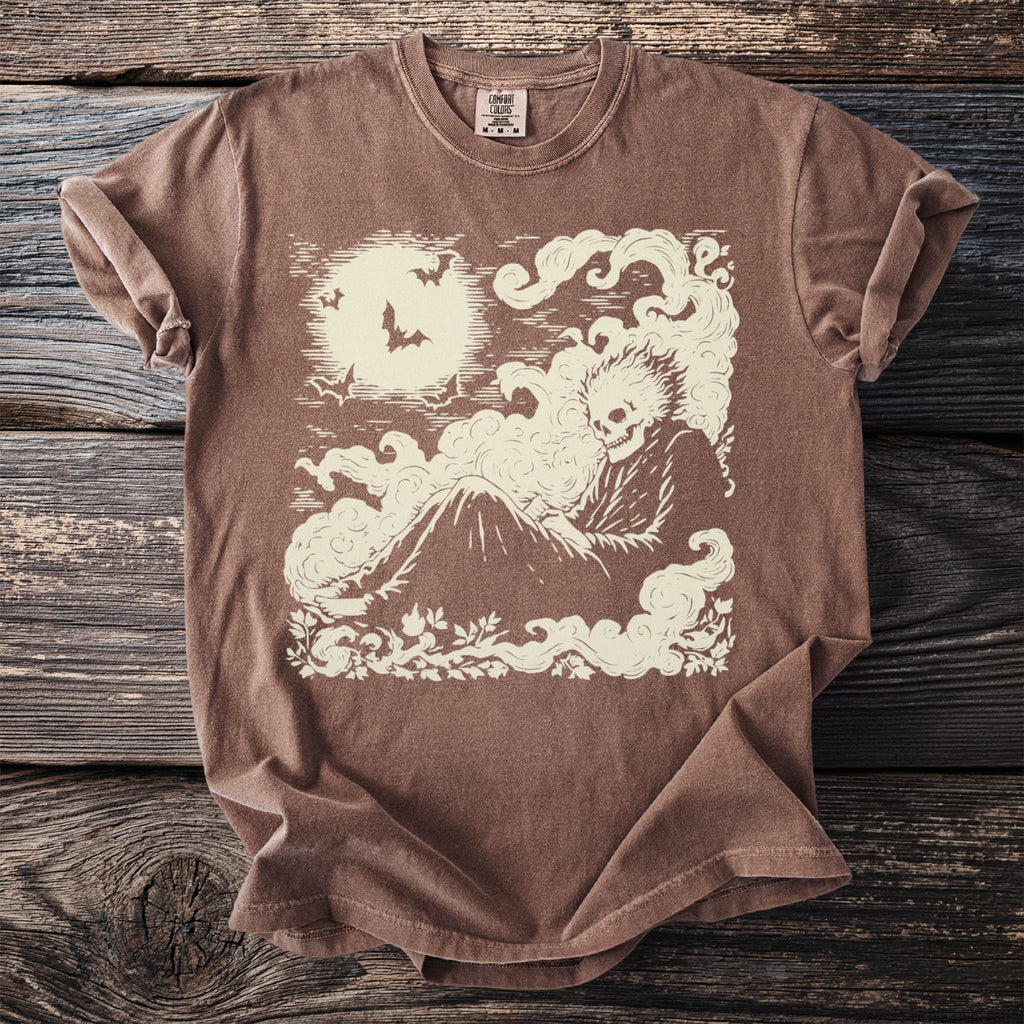Brown t-shirt with a cream graphic of a skeleton in smoke under a moon with bats.