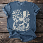 Blue t-shirt with a cream graphic of a wizard, owl, moon, and forest elements.