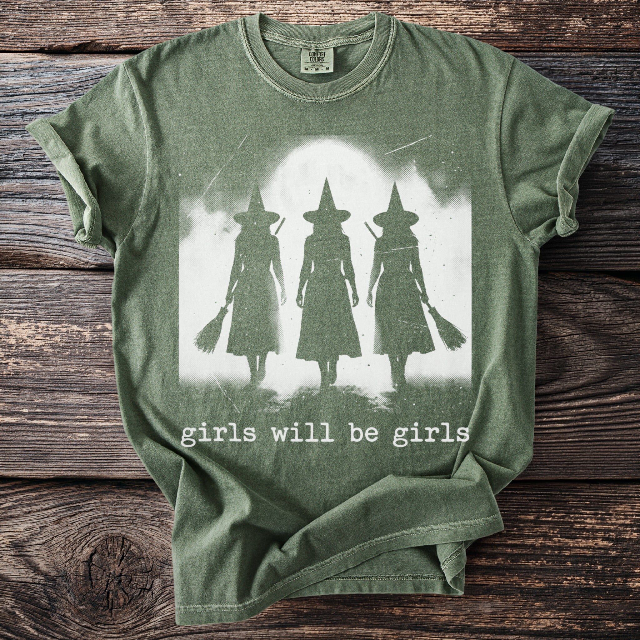Green t-shirt with three witch silhouettes and text "girls will be girls".
