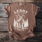 Brown t-shirt with a graphic of Leshy, a slavic forest god, with a deer headdress and a dog.