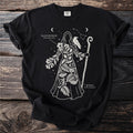 Black t-shirt with white line art illustration of a figure made of plants and a raven holding a staff.