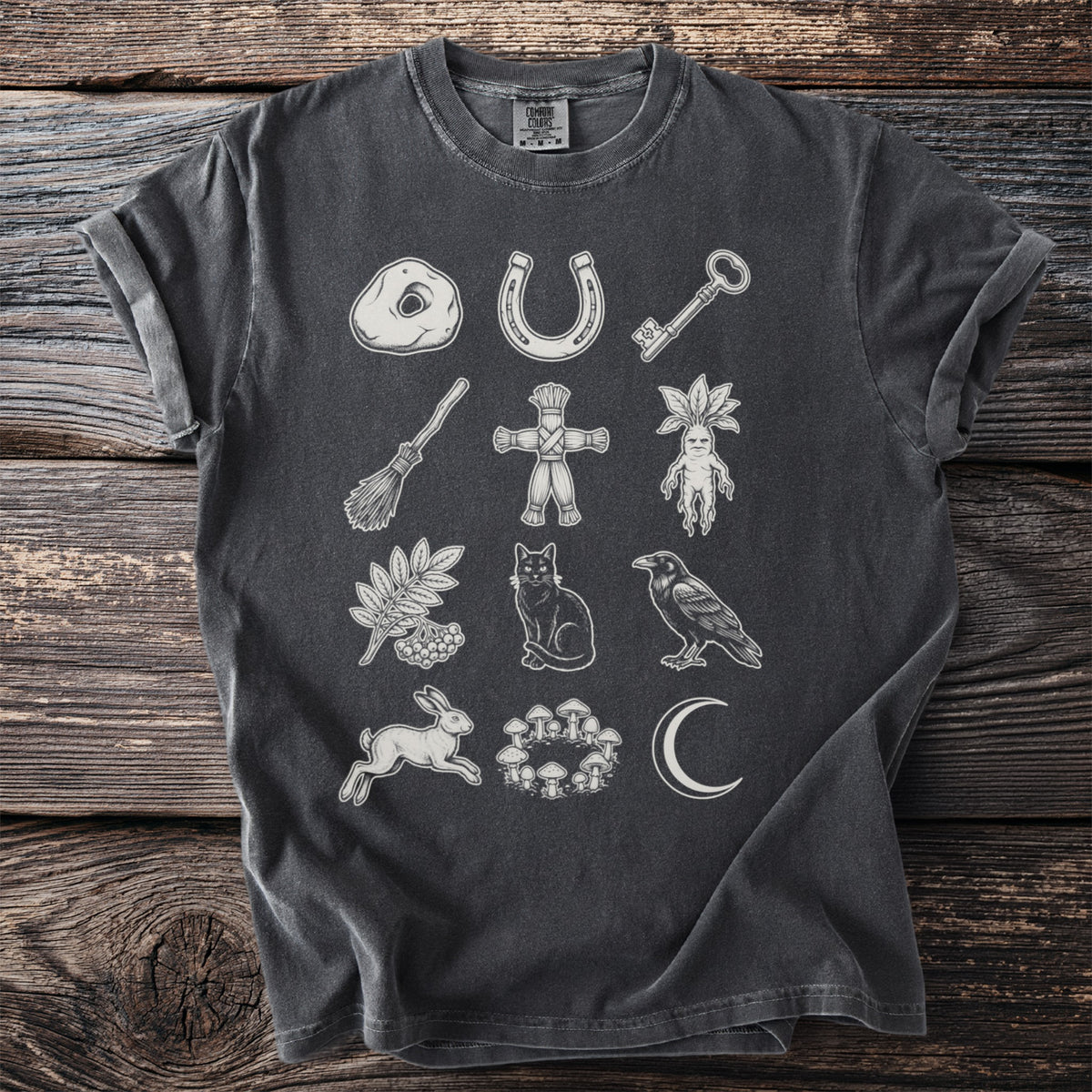 T-shirt featuring a mystical design of a horseshoe, key, broom, and cat.