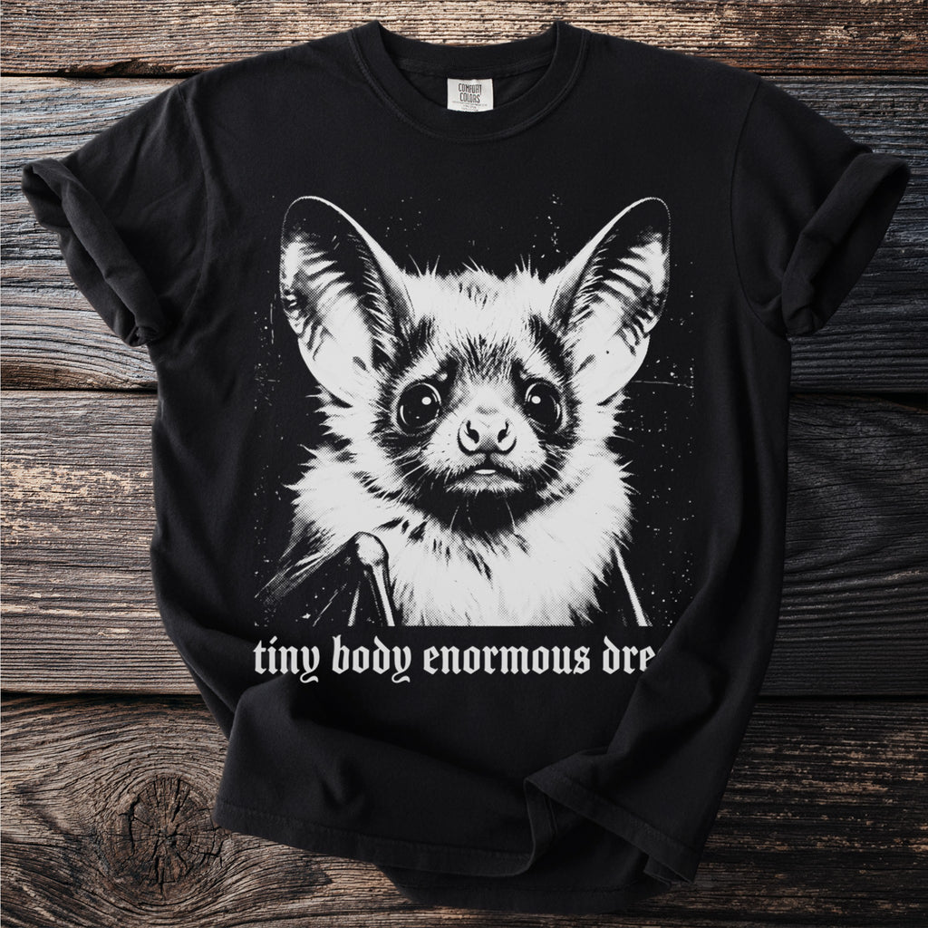 Black t-shirt with a print of a bat and text "tiny body enormous dre".