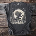 Dark t-shirt with a linocut design of Krampus carrying a tree and sack through a snowy forest.