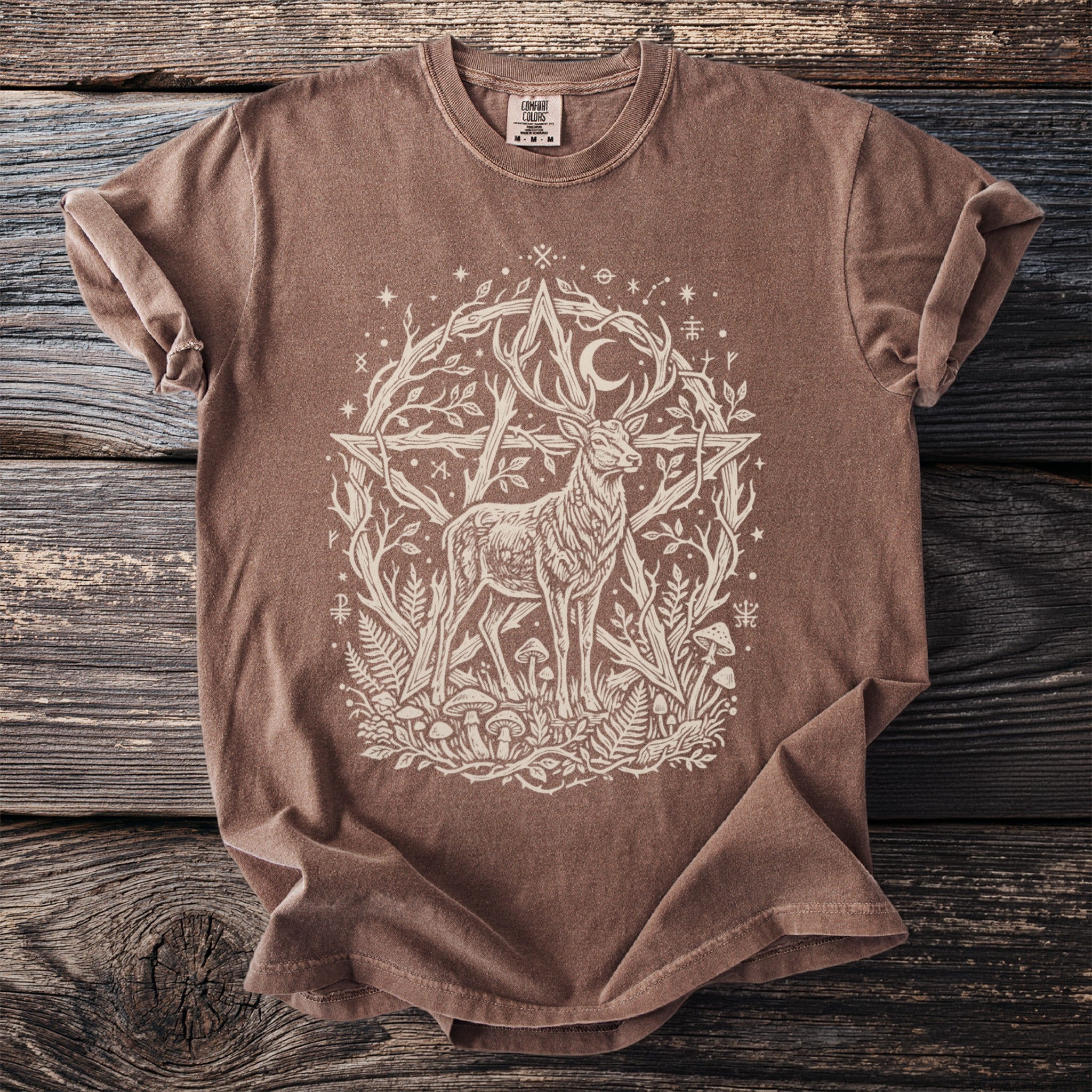 Brown t-shirt with white graphic of a deer surrounded by a pentagram, moon, plants, and symbols.