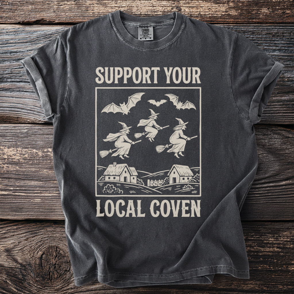 Dark grey t-shirt with graphic that says "Support Your Local Coven" featuring witches and bats.