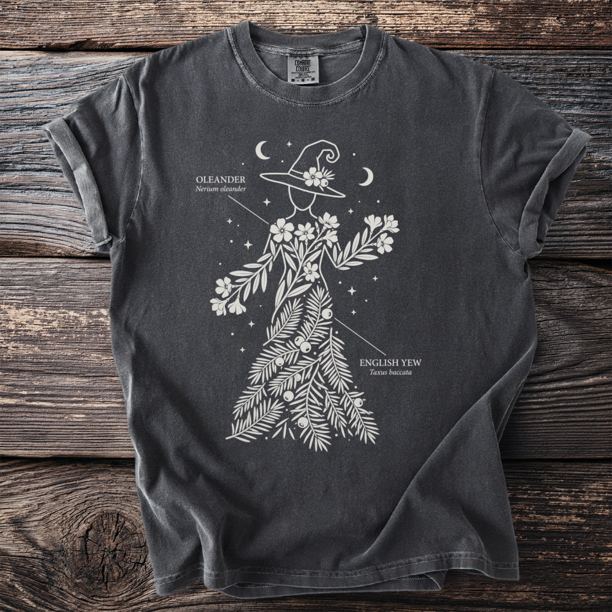 Dark t-shirt with a white graphic of a witch hat and botanical elements, labeled Oleander and English Yew.