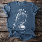 Blue t-shirt with white crow holding a decorative ornament against a starry background.