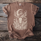 Brown t-shirt with a cream graphic depicting a raven on a crescent moon above a deer skull.