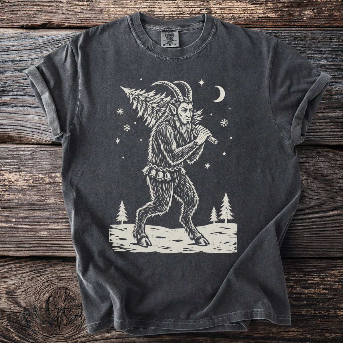 Pepper gray t-shirt with a cream folk-cut print: Krampus walks through the snow with a freshly cut fir tree over one shoulder.