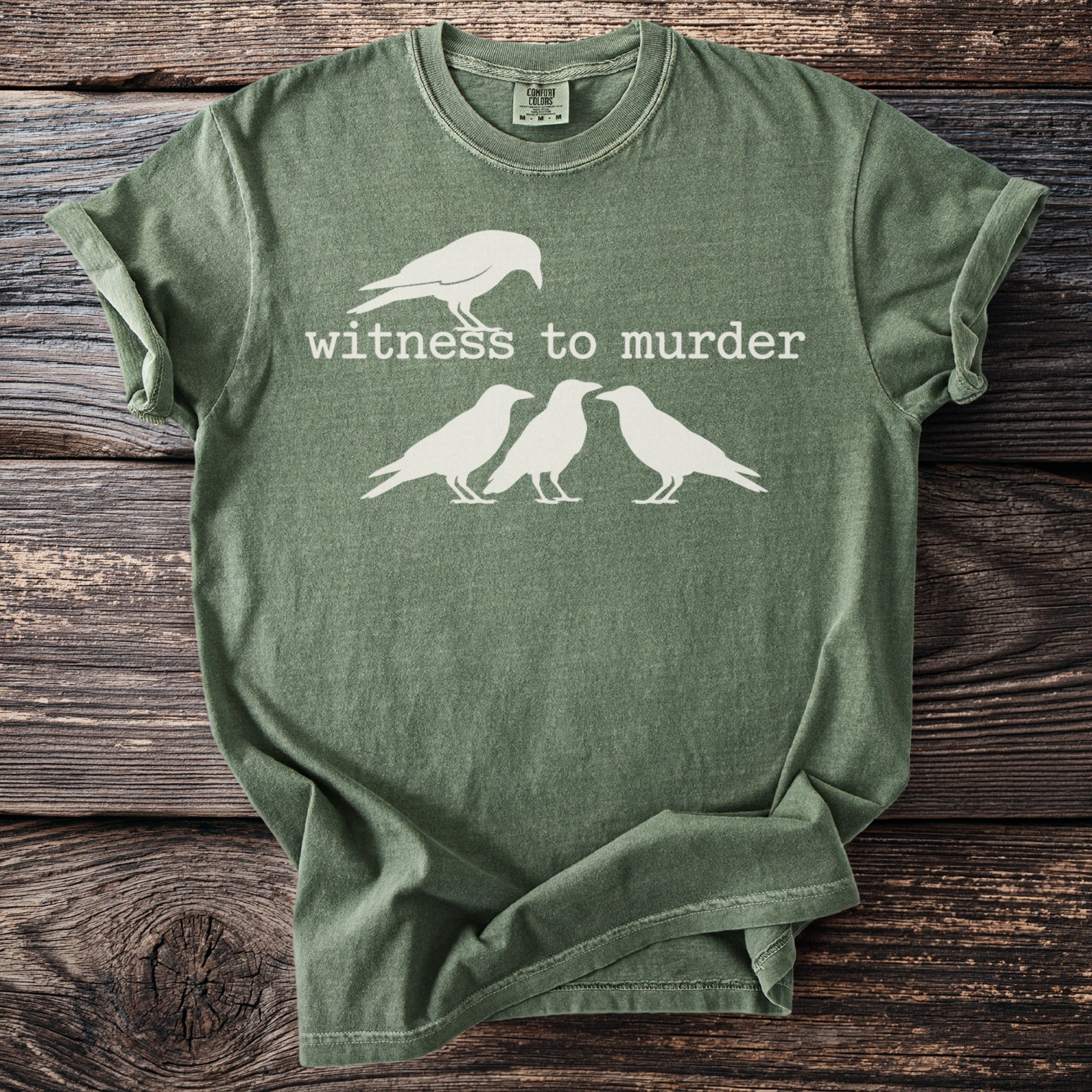 Green t-shirt with white text "Witness to Murder" and four white crows.