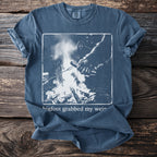 Blue t-shirt with a graphic of Bigfoot by a campfire and text "bigfoot grabbed my weir".