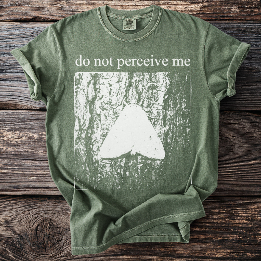 Green t-shirt with white text "do not perceive me" and a moth graphic.